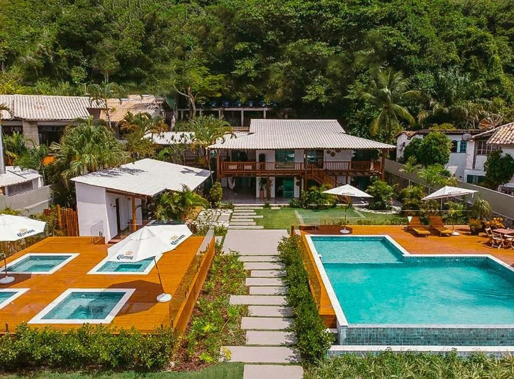 Vista aérea do complexo aquático com piscina de borda infinita, hidromassagens e a casa principal