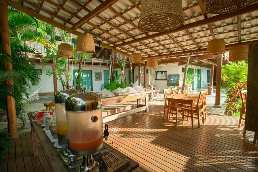 Deck do café sob pergolado de madeira, com sucos e luminárias de palha