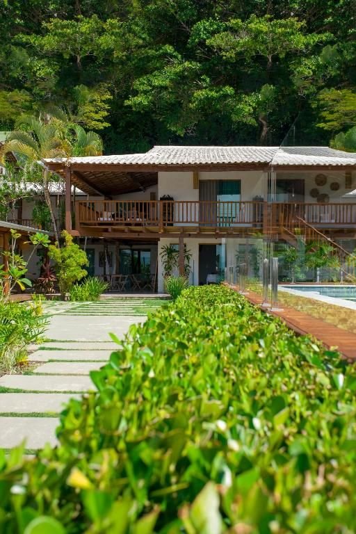 Fachada da casa principal com varandas de madeira e mata atlântica ao fundo