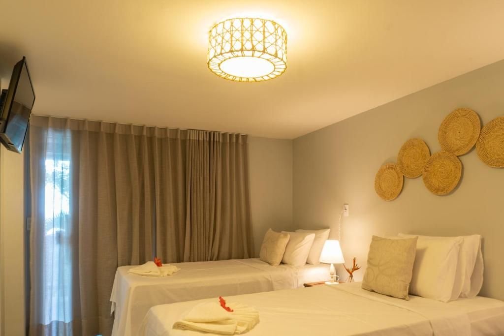Suíte com duas camas, cortinas e luminária de teto